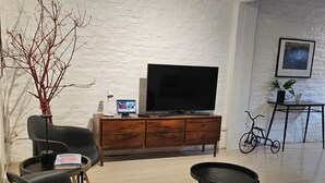 Una sala de estar moderna con televisor de pantalla plana, un sofá, una mesa de centro y una estantería.