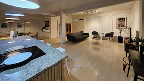 Amplia sala de estar con cocina, sofá y mesa de comedor.