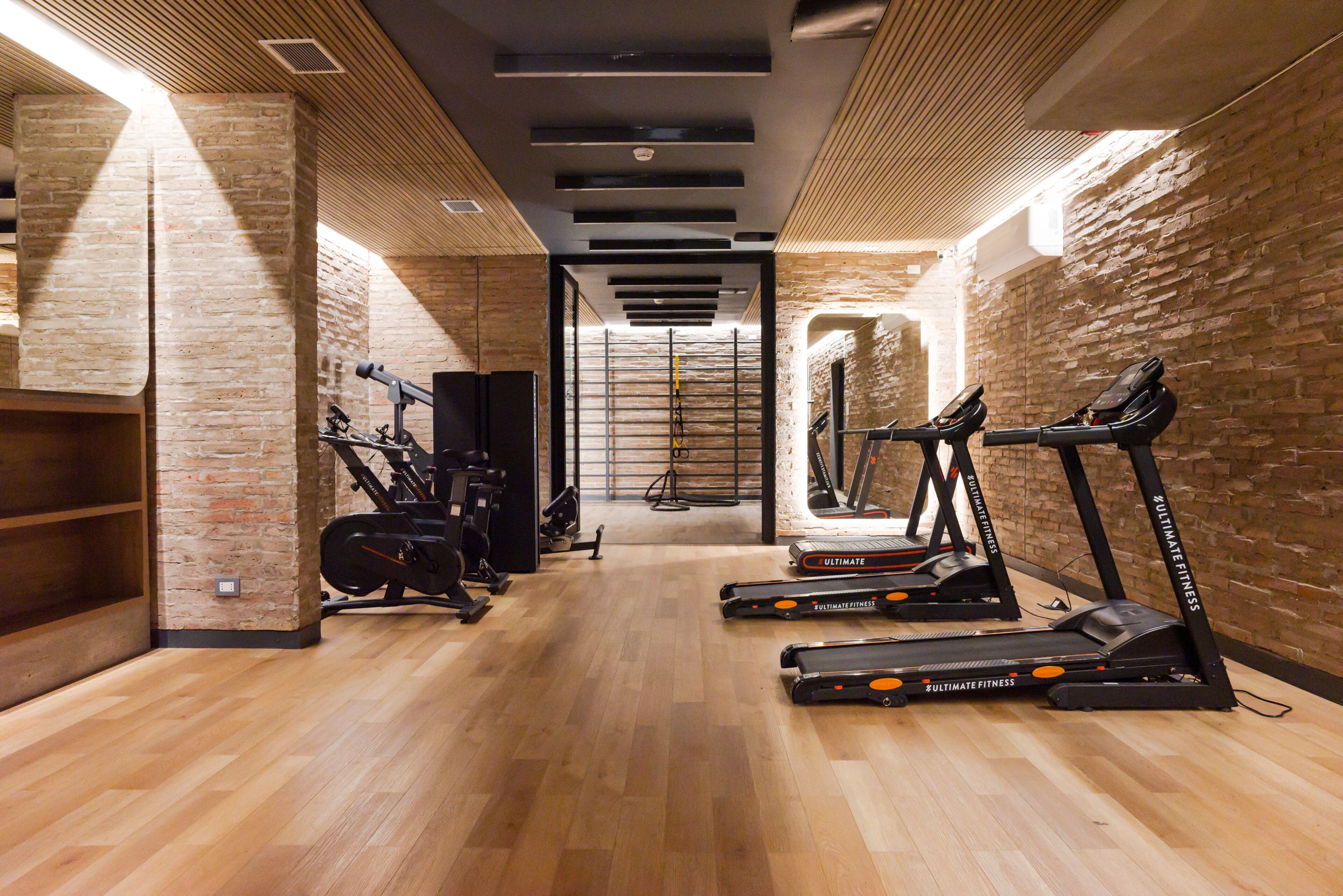 Un gimnasio con cintas de correr, bicicletas estáticas y máquinas de pesas.