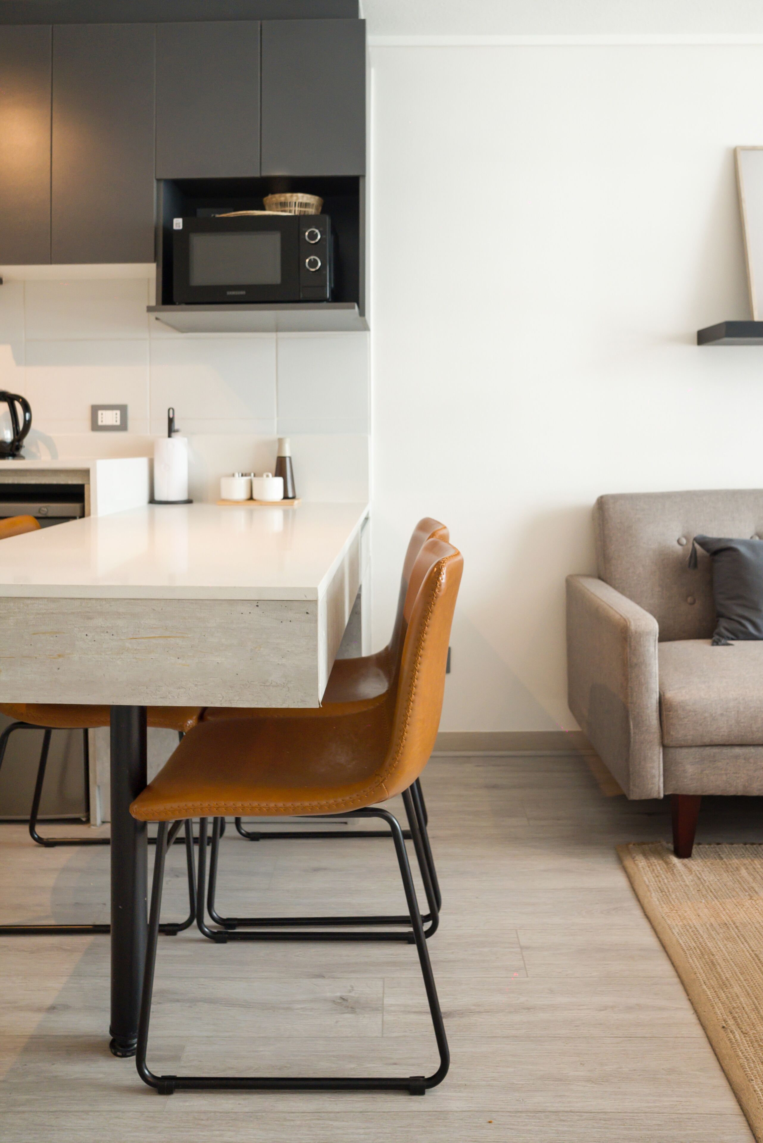 Una cocina moderna con microondas, una mesa de comedor con sillas y un sofá en la sala.