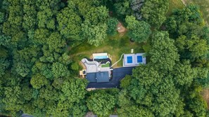 Vista aérea de una propiedad con piscina, terraza cubierta y amplia zona abierta.