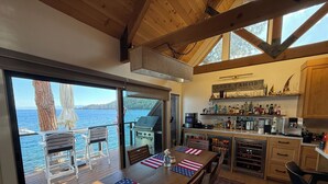 Une cuisine avec un coin bar, une table à manger agrémentée d’un set de table orné du drapeau américain, et une vue sur l’eau.