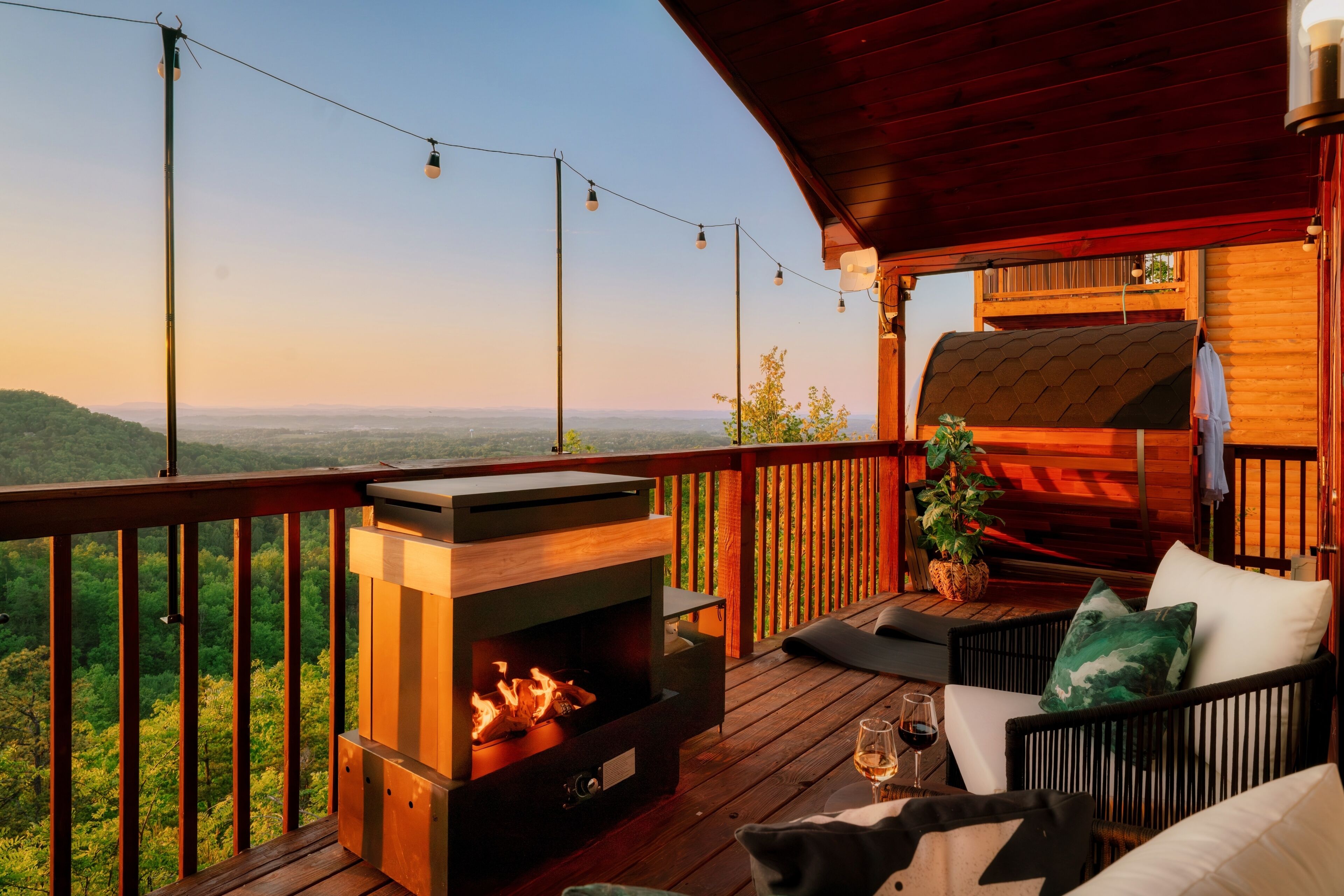 A wooden deck with a fireplace, outdoor seating, and a view of the landscape.