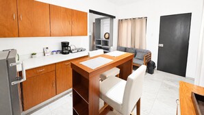 A compact kitchen with wooden cabinets, a coffee maker, and a dining area with a table and chairs.