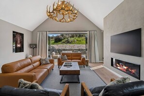 Ein modernes Wohnzimmer mit Kamin, Ledersofas, einem Couchtisch und einem großen Fernseher.