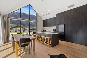 Eine moderne Küche mit einer großen Kochinsel, dunklen Holzschränken und Blick auf Berge.