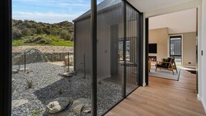 A modern interior with a large sliding glass door leading to a rocky outdoor area. - Modern Alpine Retreat in Jacks Point (Queenstown)