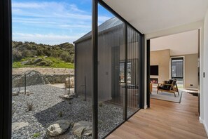 Ein modernes Interieur mit einer großen Schiebeglastür, die zu einer felsigen Außenanlage führt.