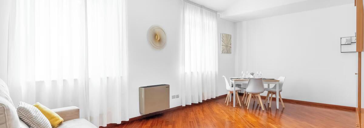 Una sala de estar moderna con comedor, paredes blancas y suelo de madera.