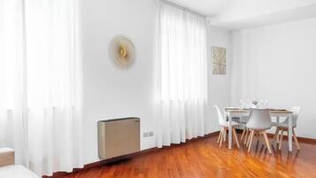 Una sala de estar moderna con comedor, paredes blancas y suelo de madera.