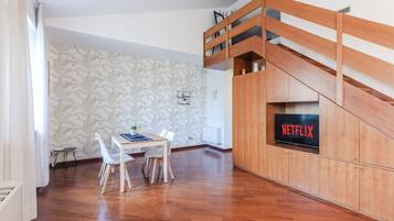 Ein moderner Wohnbereich mit Essplatz, einer Treppe und einem Fernseher, der das Netflix-Logo zeigt.