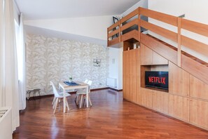 Ein moderner Wohnbereich mit Essplatz, einer Treppe und einem Fernseher, der das Netflix-Logo zeigt.