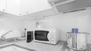 Une cuisine équipée d’un four à micro-ondes, d’un évier, d’un égouttoir, d’une casserole sur la cuisinière et d’un lave-vaisselle.