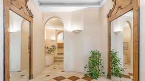 Un couloir doté d’un sol à carreaux, de murs recouverts de miroirs et de plantes en pot.