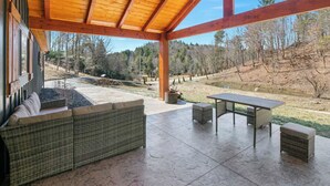 Eine überdachte Terrasse mit einem Rattan-Sofa, einem Tisch und einer Bank.