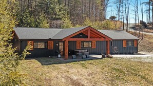 Eine Hütte mit überdachter Veranda, einem Essbereich und einer kleinen Sitzgelegenheit im Freien.