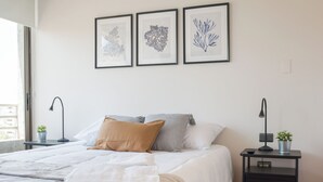 A bedroom with a bed, bedside tables, a nightstand, and framed artwork on the wall. - 1BR in Heart of Providencia Urban Style (Providencia)