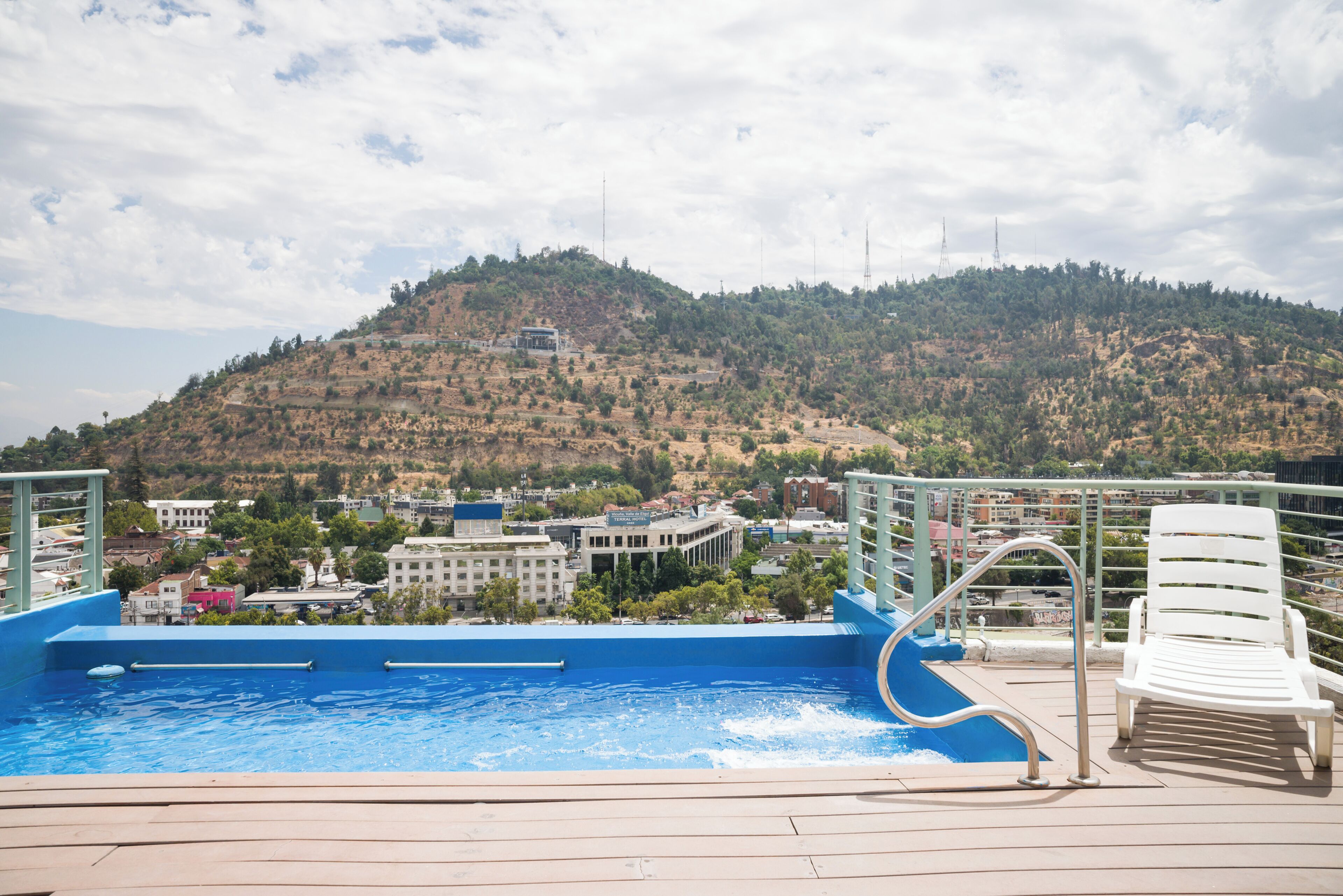An outdoor swimming pool with a view of a hillside town and buildings.
