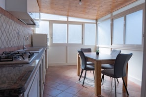 Una cocina con estufa a gas, un lavamanos y una zona de comedor con mesa y sillas.