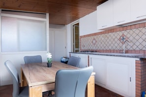 Una cocina con gabinetes blancos, un protector contra salpicaduras de azulejos y un techo de madera.