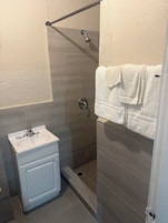 A bathroom with a shower, a sink, and a towel rack.