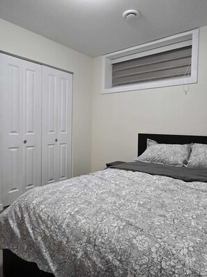Una camera da letto con un letto, una finestra con persiane e una porta bianca.