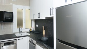 Een moderne keuken met witte kasten, een roestvrijstalen koelkast, een vaatwasser en een magnetron.