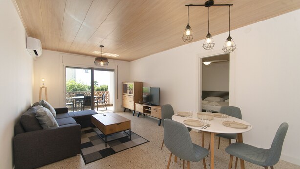 Een moderne woonkamer met een bank, salontafel, eettafel met stoelen en een televisie.