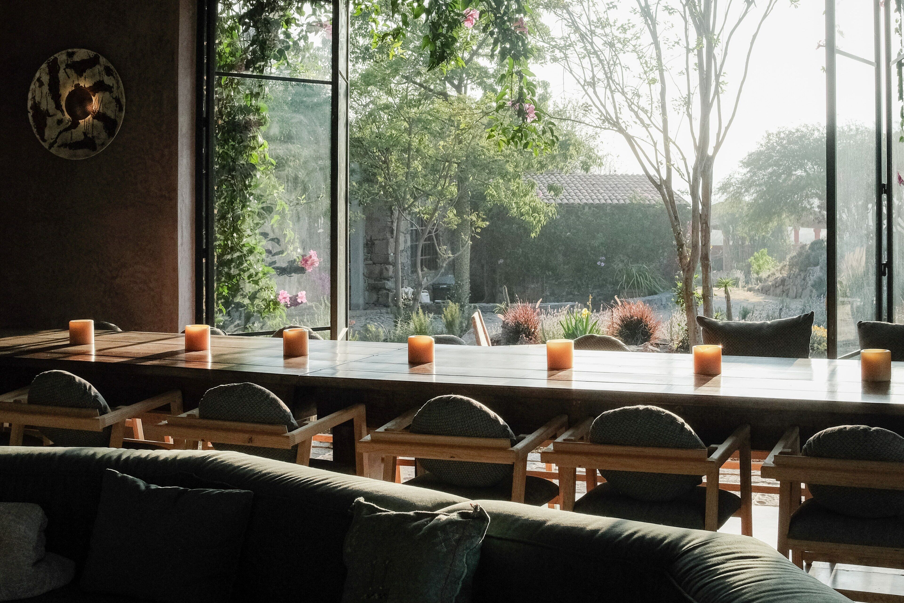 Una habitación con un ventanal grande, una mesa de comedor con velas y un sofá verde.