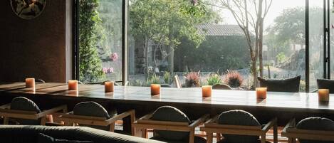 Una habitación con un ventanal grande, una mesa de comedor con velas y un sofá verde.