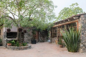 Un patio con un edificio de piedra, una puerta de madera y un ventanal grande.