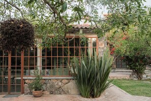 Un edificio con fachada de piedra, ventanas grandes y techo de tejas.