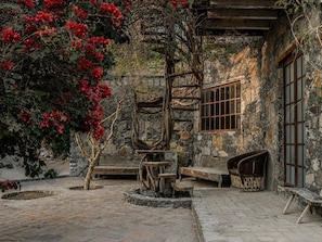 A rustic stone building with a wooden spiral staircase, a bench, and a small table. - Casa X  (San Miguel de Allende)