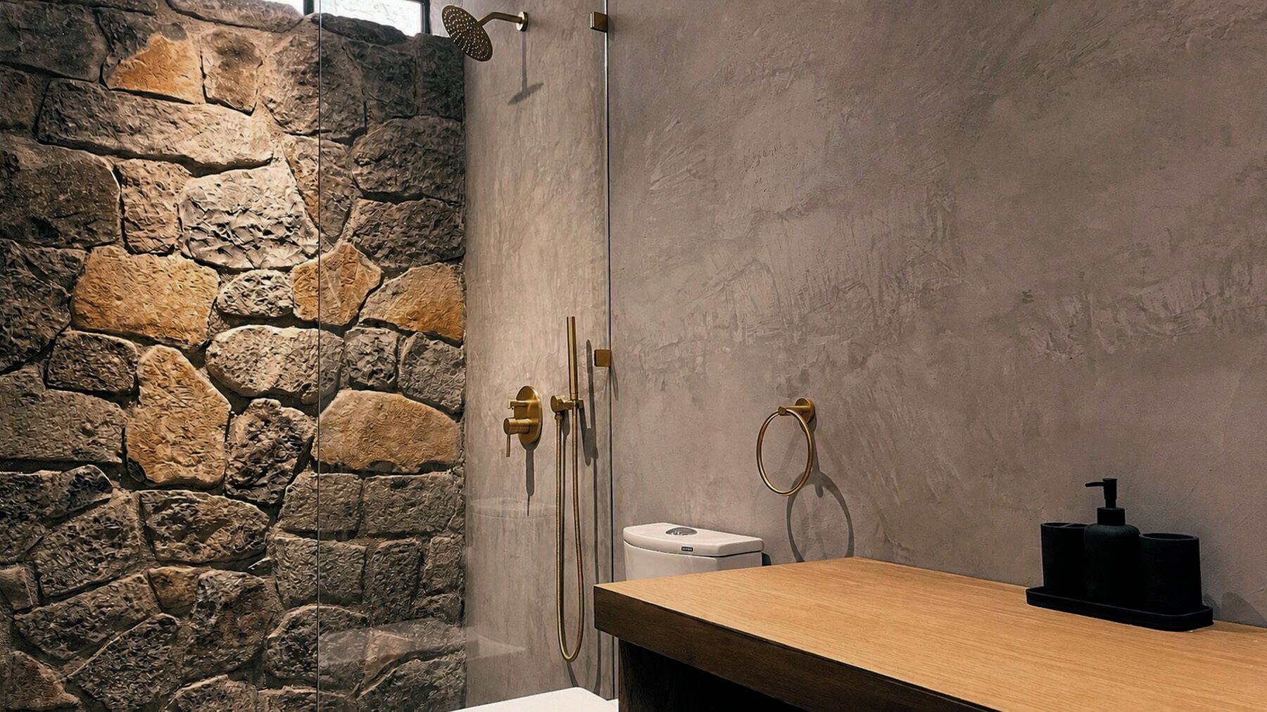 Un baño con pared de piedra, tocador de madera, inodoro y ducha con puerta de vidrio.