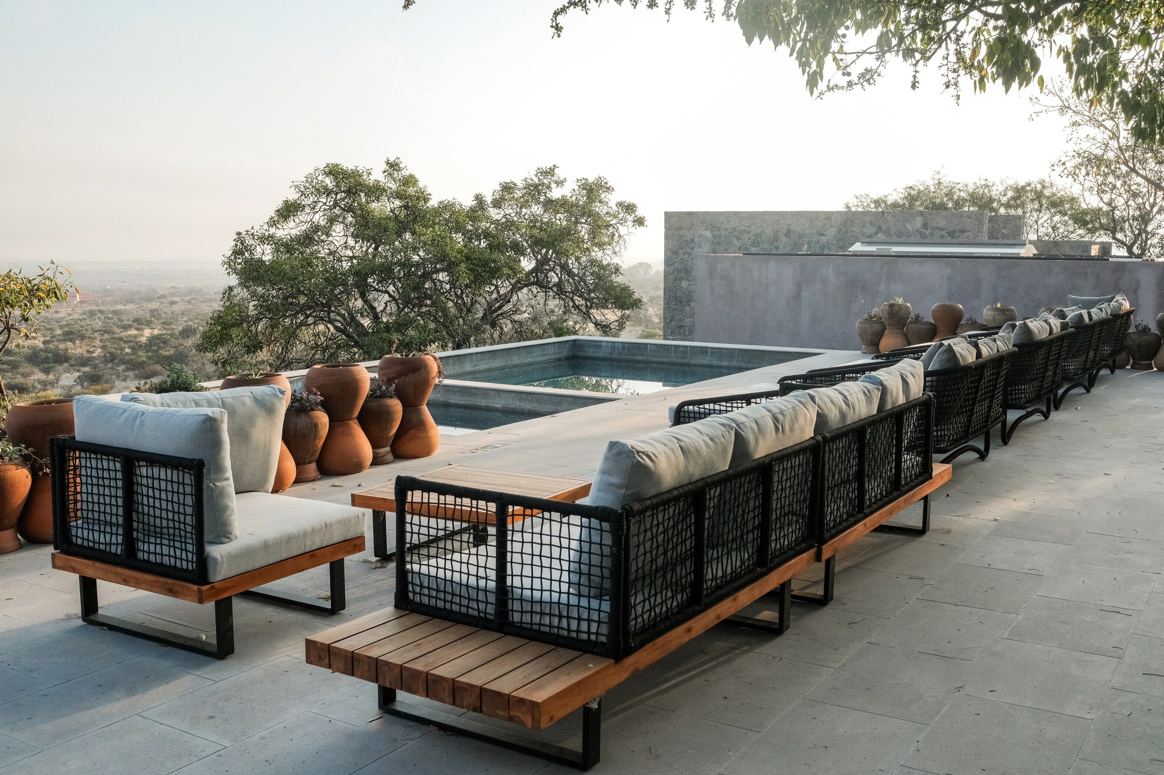 A rooftop terrace with outdoor seating, a pool, and potted plants.