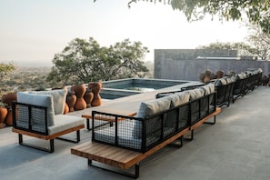 Una terraza en la azotea con mobiliario exterior, piscina y plantas en macetas.
