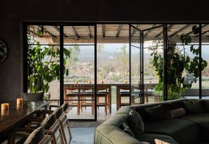 Een modern interieur met een eethoek, een bank en grote ramen met uitzicht op het landschap.