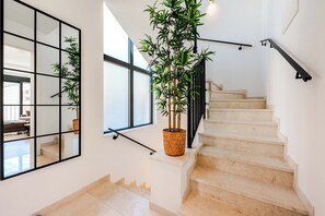 Uma escadaria com uma planta de bambu em vaso, um corrimão de metal preto e um espelho grande na parede.