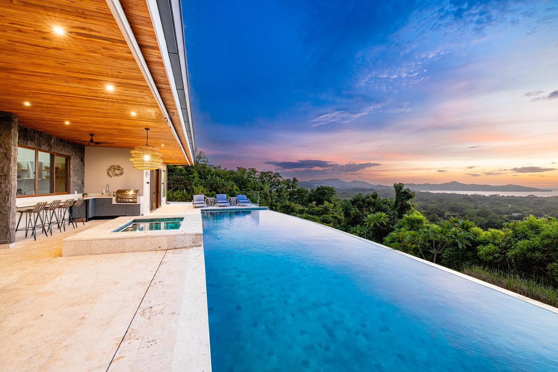 Ein modernes Haus mit Swimmingpool, Bar und Blick auf die Landschaft.