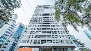 Um edifício moderno com fachada de vidro, entrada imponente e placa indicando área de vendas.
