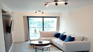 Uma sala de estar moderna com um sofá, uma mesa de centro e uma TV de tela plana na parede.
