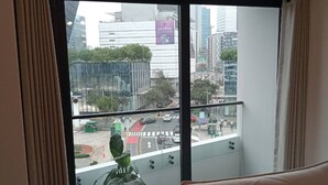 Quarto de hotel com uma janela grande, um vaso de planta e um sofá.