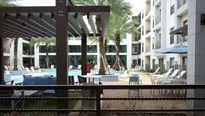 A hotel pool area with lounge chairs, a small table, and palm trees. - 5 min from NRG - Pool, Gym & Free Parking (Houston)