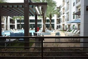 Ein Hotelpoolbereich mit Liegestühlen, einem kleinen Tisch und Palmen.