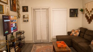 A living room with a sofa, a coffee table, a TV, and a door with a window. - 5 min from NRG - Pool, Gym & Free Parking (Houston)