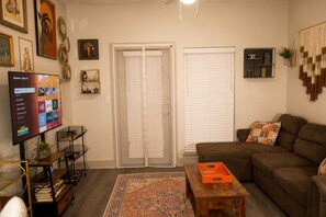 Ein Wohnzimmer mit einer Couch, einem Couchtisch, einem Fernseher und einer Tür mit Fenster.