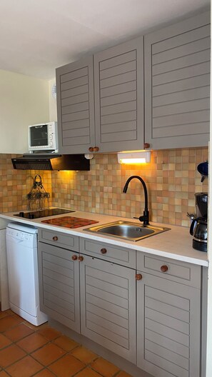 A compact kitchen with a dishwasher, a microwave, a sink, and a coffee maker. - Appartement avec PISCINE/TENNIS dans petite residence  proche village provencal (Sablet)