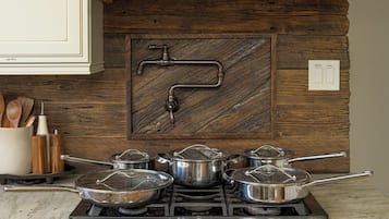 A kitchen with a gas stove, pots, wooden utensils, and a coffee filter.