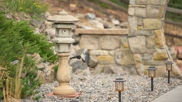 A stone lantern pathway with a pagoda-style structure in the center, surrounded by gravel and greenery.