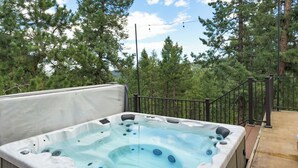 A hot tub with a metal railing and a view of trees. - 3-bdrm home in Evergreen w/sweeping mountain views, hot tub, sauna, & fire place (Evergreen)